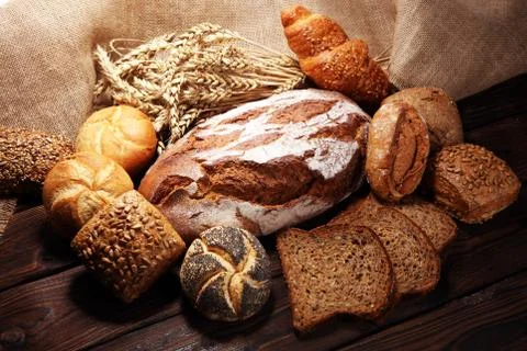 Different kinds of bread and bread rolls on board from above. Stock Photos