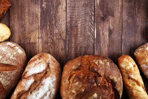 Different kinds of bread and bread rolls on board from above. Kitchen or bake Stock Photos