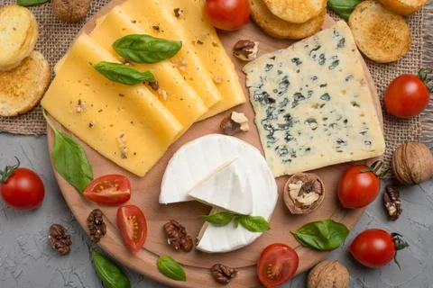 Different kinds of cheeses, with basil, cherry tomatoes, croutons from baguet Stock Photos