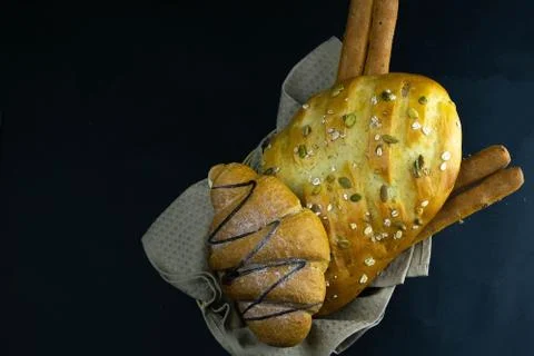 Different kinds of fresh bread with grain on black rustic background. Stock Photos