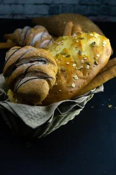 Different kinds of fresh bread with grain on black rustic background. Stock Photos