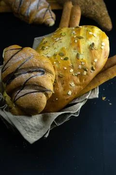 Different kinds of fresh bread with grain on black rustic background. Stock Photos