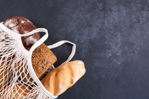 Different kinds of fresh bread in white mesh tote bag Stock Photos