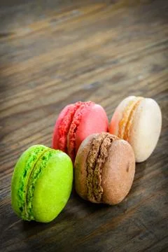 Different kinds of macaroons in stack on wooden background, selective focus Stock Photos