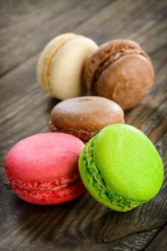Different kinds of macaroons in stack on wooden background, selective focus Stock Photos
