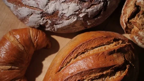 Different kinds of organic bread and a croissant on a rotating wood background. Stock Footage 145973157