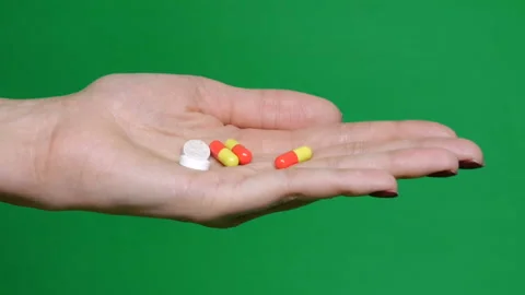 Different kinds pills falling on green background in hand. Multi-colored tablets Video stock 126862642