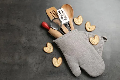 Different kitchen utensils in oven mitten and cookies on grey table, flat l.. 写真素材