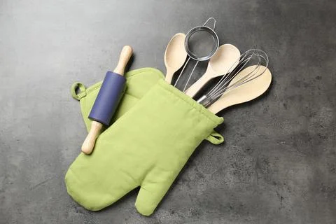Different kitchen utensils in oven mitten on grey table, flat lay 写真素材