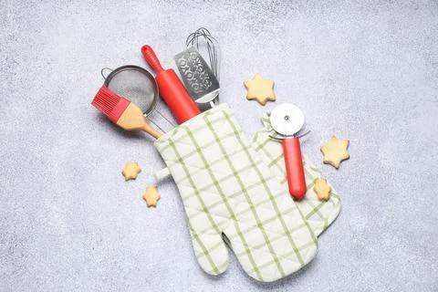 Different kitchen utensils in oven mitten and cookies on light table, flat la 写真素材