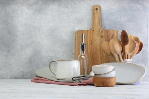Different kitchenware and dishware on white wooden table against textured wal Stock Photos