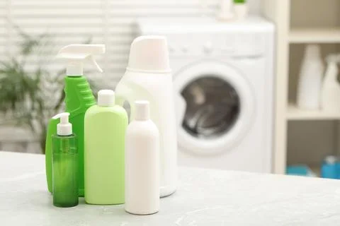 Different laundry detergents on light marble table in bathroom. Space for tex Stock Photos