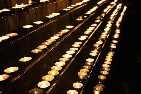 Different lighted candles stand on a platform in the church Contrast of lig.. Stock Photos