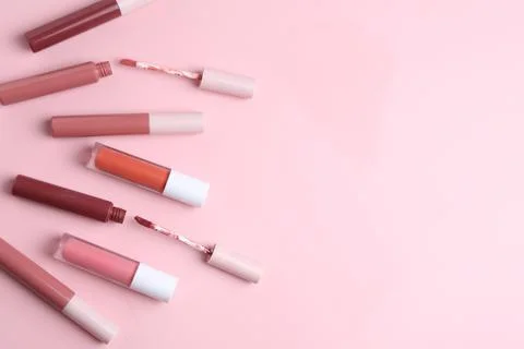 Different lip glosses and applicators on pink background, flat lay. Space f.. Stock Photos