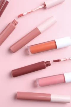 Different lip glosses and applicators on pink background, flat lay Stock Photos