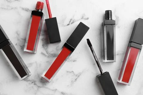 Different lip glosses and applicators on white marble table, flat lay Stock Photos