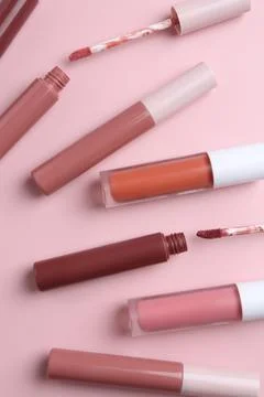 Different lip glosses and applicators on pink background, flat lay Stock Photos