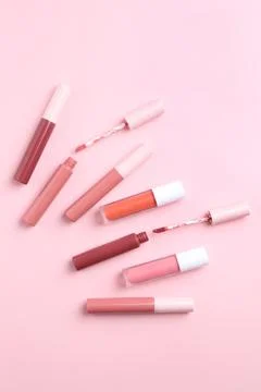 Different lip glosses and applicators on pink background, flat lay Stock Photos