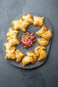 Different little cocktail EMPANADAS on stone plate with tomato sauce and Stock Photos