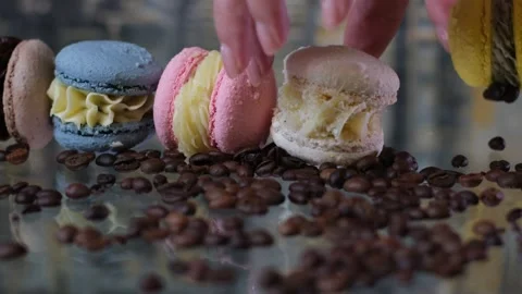 Different macaroons lie on the glass table female hands pick up French dessert a Stock Footage 247722439