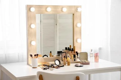 Different makeup brushes and decorative cosmetics on dressing table with mirr Stock Photos