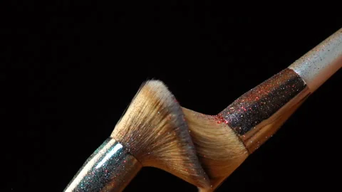 Different makeup brushes with powder flying on black background Stock Footage 122127109