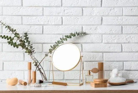 Different makeup products with mirror and eucalyptus branches on white table  Stock Photos