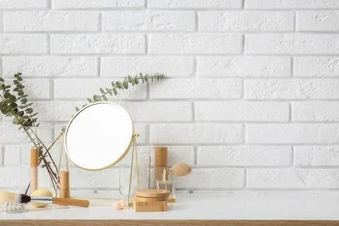 Different makeup products with mirror and eucalyptus branches on white table  Stock Photos