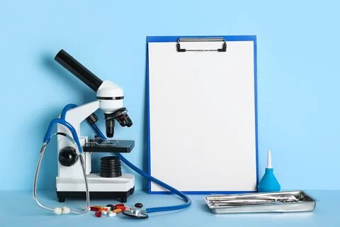 Different medical tools with microscope and clipboard on blue background. Nob Фото