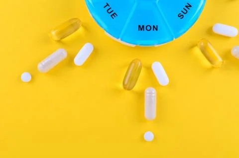 Different medicines for one week and a pills box on yellow background with copy Stock Photos