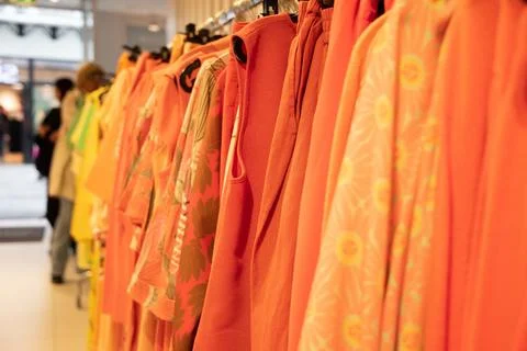 Different models orange blouses in second hand store grouped in the same color Stock Photos