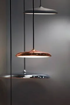 Different modern streamlined mirror copper chandeliers. Metal copper disk sha Stock Photos