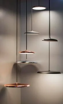 Different modern streamlined mirror copper chandeliers. Metal copper disk sha Stock Photos