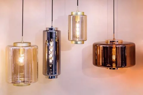 Different modern streamlined mirror copper chandeliers. Cylindrical metal cop Stock Photos