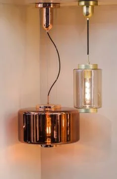 Different modern streamlined mirror copper chandeliers. Cylindrical metal cop Stock Photos