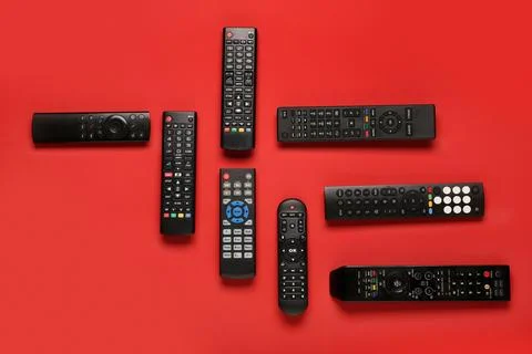 Different modern TV remote controls on red background Stock Photos