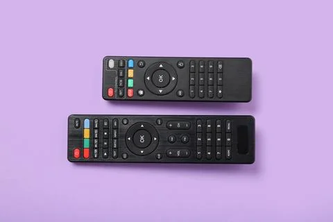 Different modern TV remote controls on purple background Stock Photos