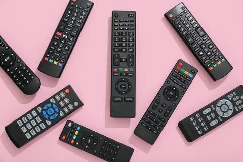 Different modern TV remote controls on pink background Stock Photos