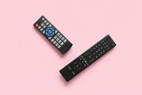 Different modern TV remote controls on pink background Stock Photos