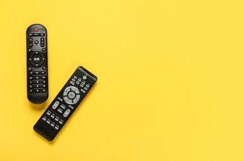 Different modern TV remote controls on yellow background Stock Photos