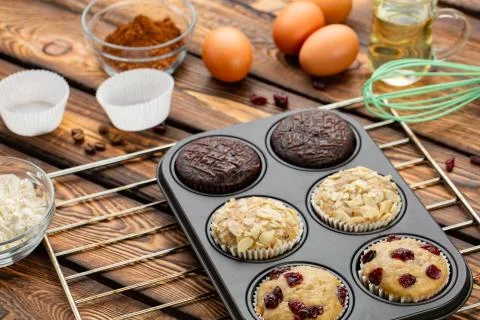 Different Muffins in bakeware or muffin pan on broun wooden background. Basic Stock Photos