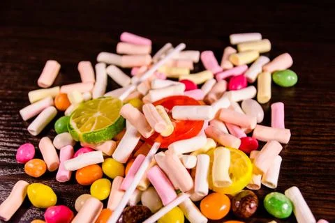 Different multi colored candies on a dark wooden table Stock Photos