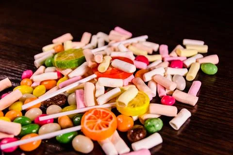 Different multi colored candies on a dark wooden table Stock Photos