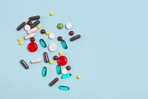 Different multi colored pills and tablets on blue background. Stock Photos