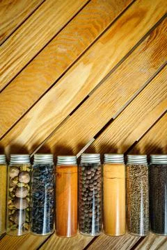 Different multi-colored spices in jars lie on a board background with copy space Stock Photos