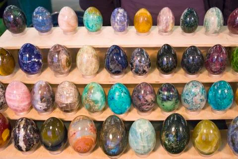 Different multicolored stone eggs arranged on a wooden rack Stock Photos