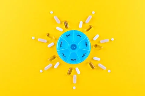 Different nutritional supplements for one week and a pills box on yellow Stock Photos