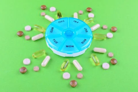 Different nutritional supplements for one week and a pills box on green Foto stock