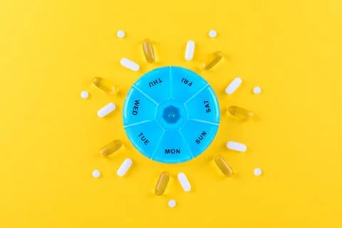 Different nutritional supplements for one week and a pills box on yellow Stock Photos