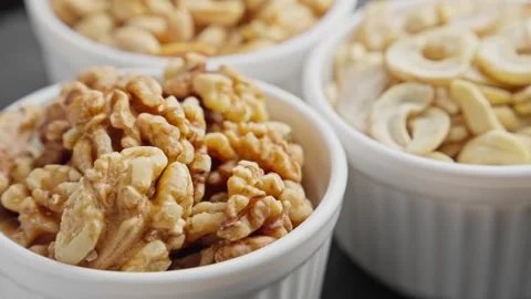 Different nuts in white bowls rotating. Cashew, peanuts, walnuts. Natural food Stock Footage 288089547